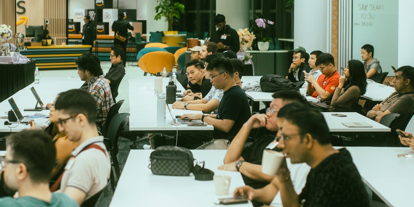 Developers with laptops and phones at long tables during a meetup
