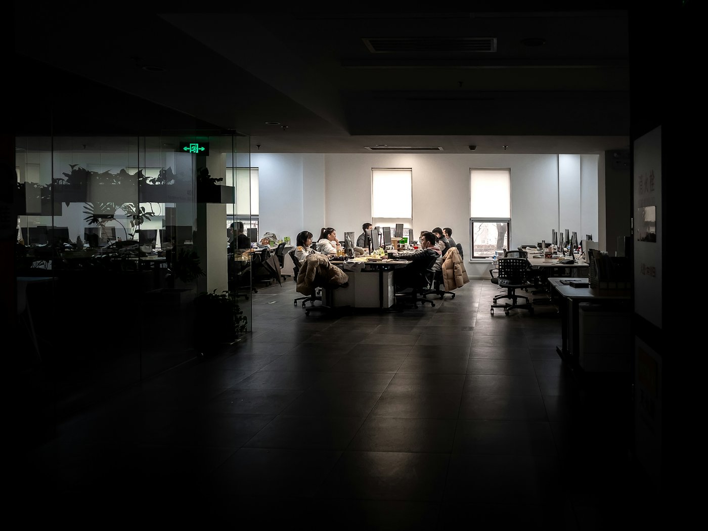 A small team still working at their desks late at night in a dark office