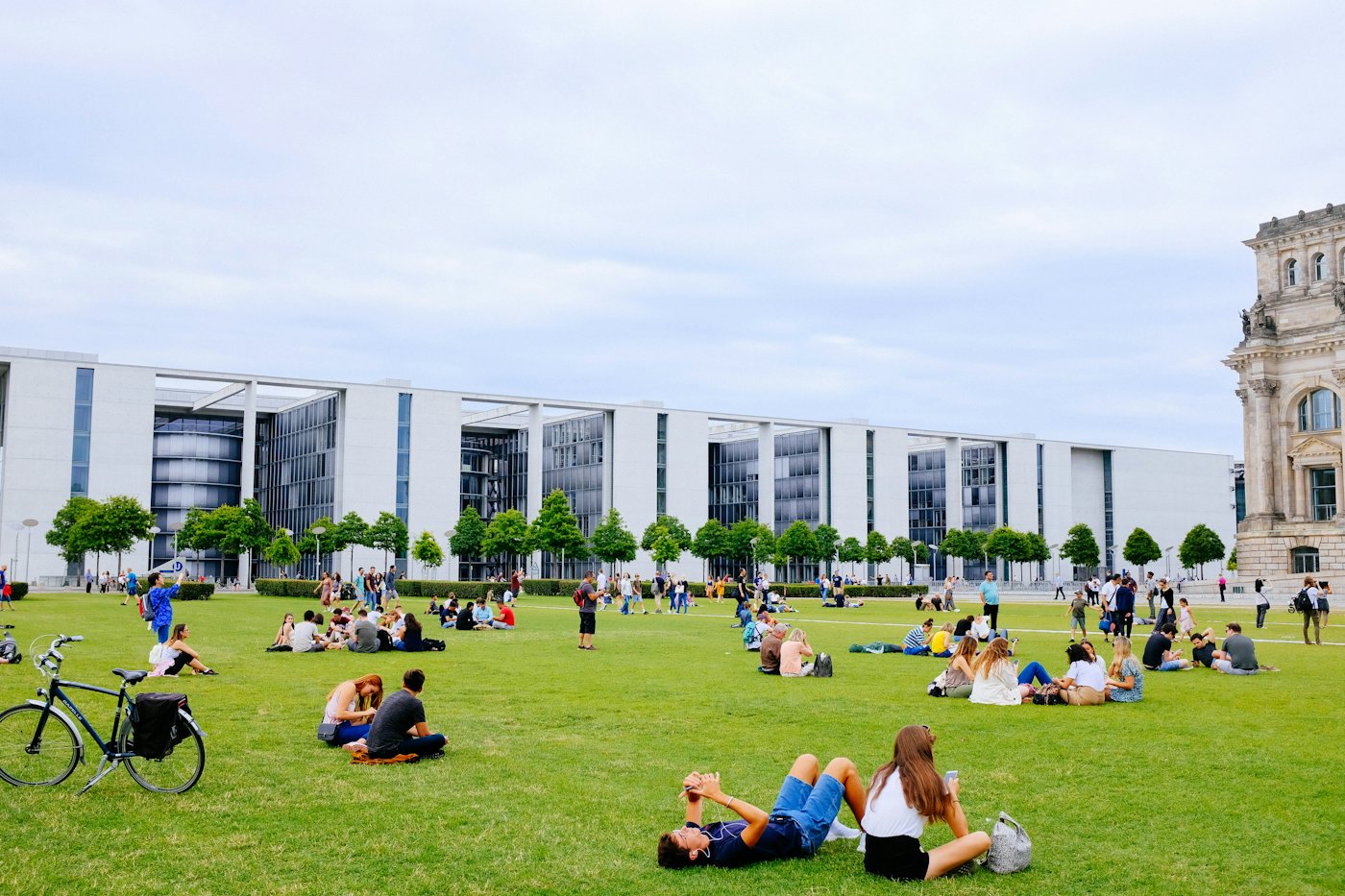 Students relaxing on a sunny campus lawn in front of university buildings