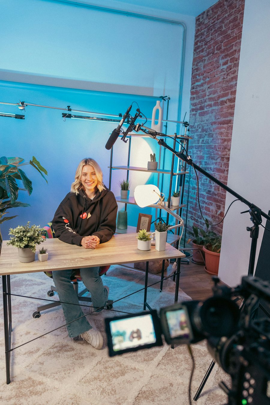 An online course creator sitting at a desk in a home studio with lights and a camera