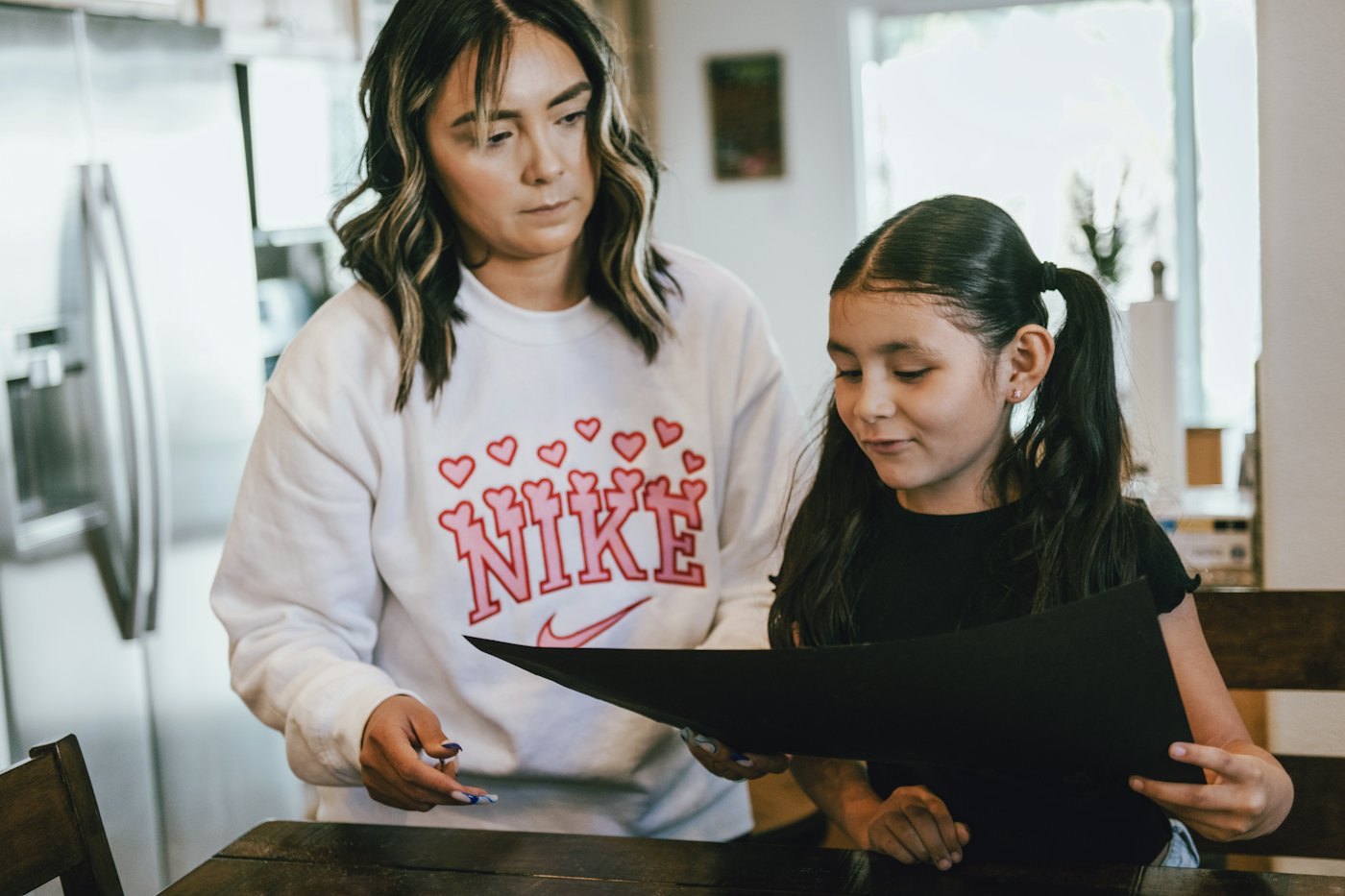 A mother and daughter looking at school papers together at the kitchen table