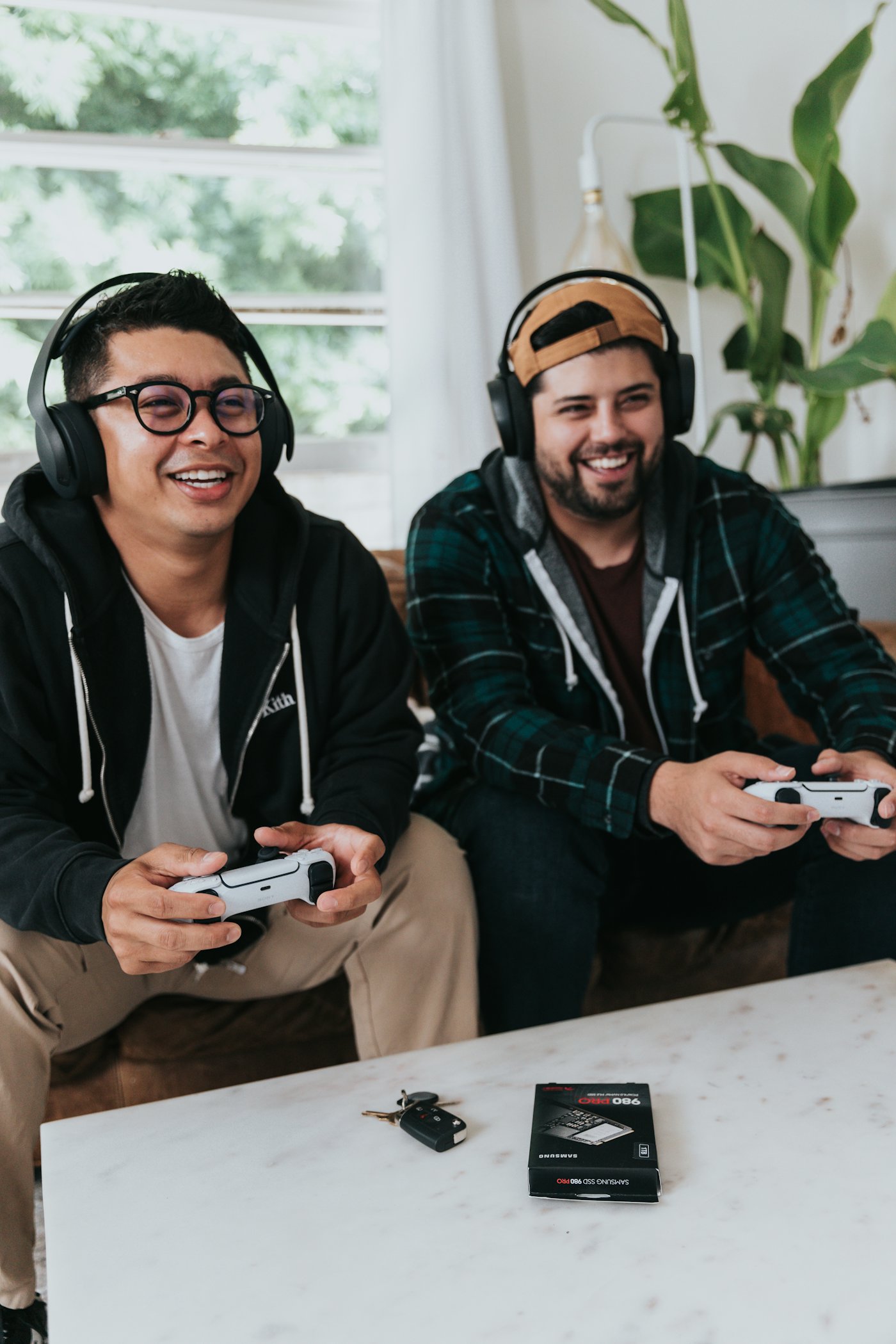 Two friends with headsets laughing while playing a game together